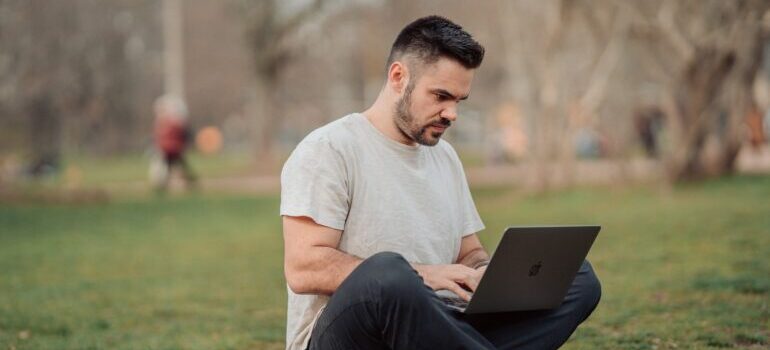 man in park doing a search on his laptop