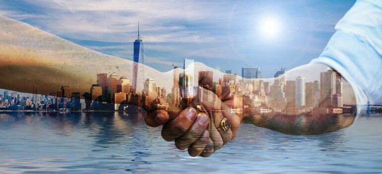 A handshake between two people with New York in the background.