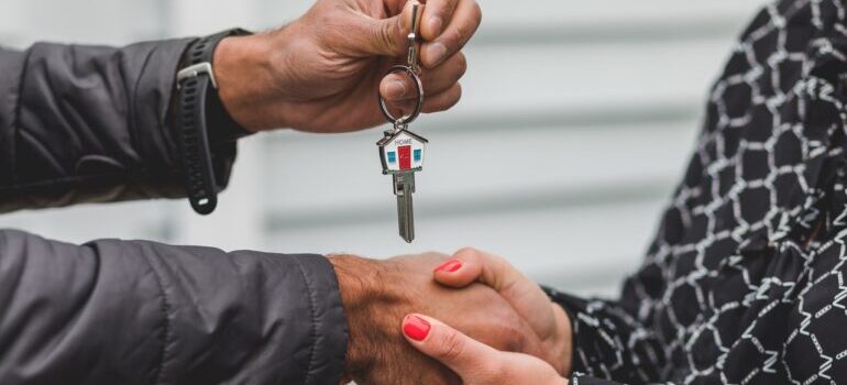 Person giving the key of a new home to another person.