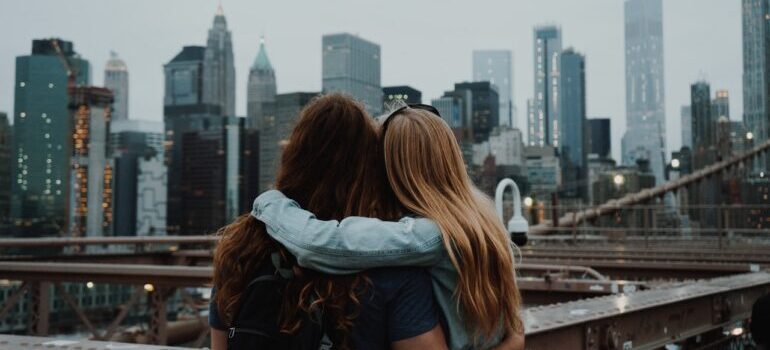 Two girls looking over New York City hugging each other
